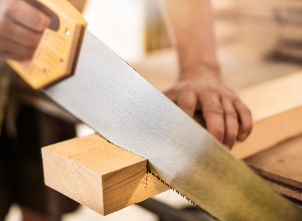 Man using a hand saw to cut wood