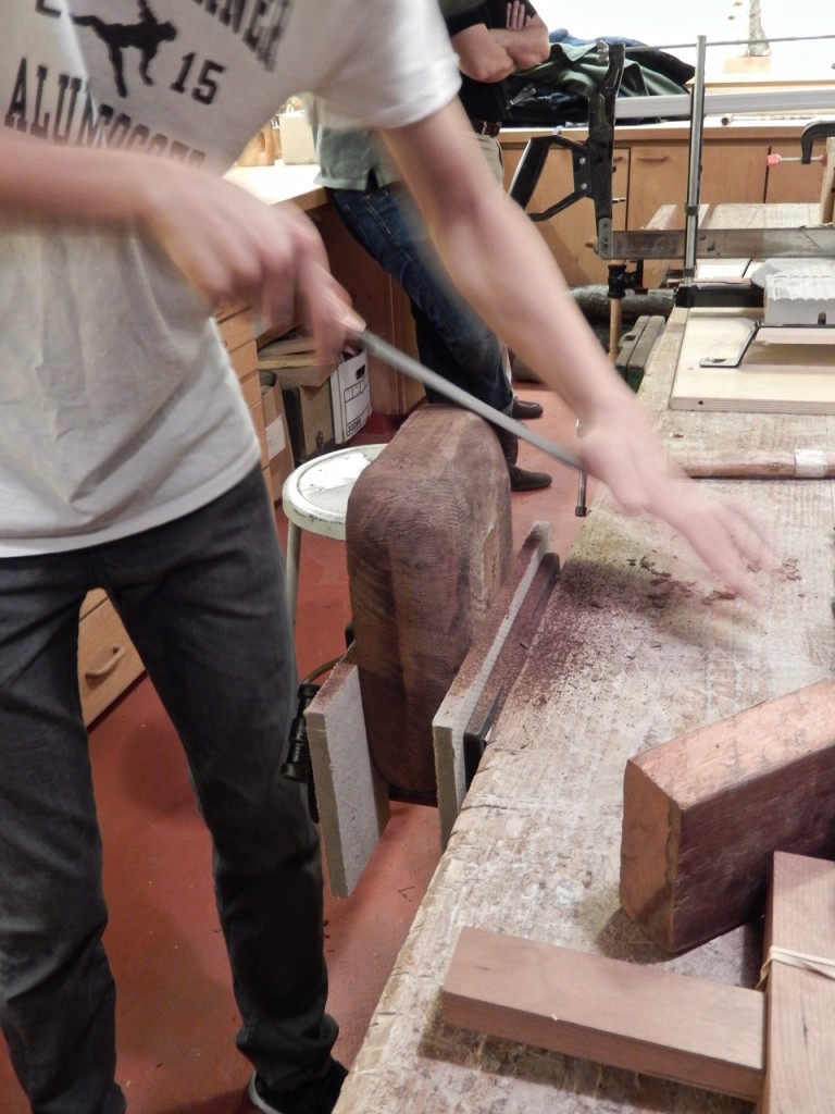 One of our 10th graders demonstrate carving a wooden bowl. In this image he rasp the bowl exterior. 