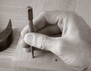 This is the proper way to hold a nail set. Resting your hand on the work helps reduce mis-strikes.