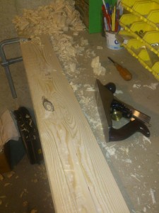 Cutting a bevel on a piece of trim with a handplane. This is a practice piece with a big knot in the middle.