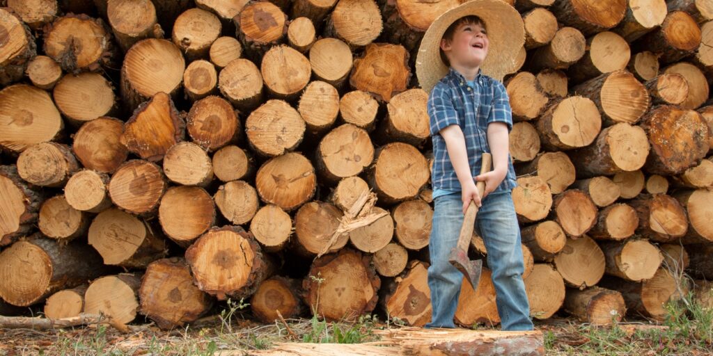 Woodcutter kid splits wood with axe